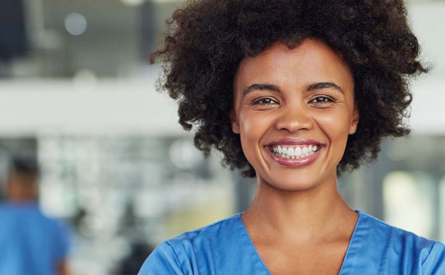 Young woman with large smile in a blue shirt, background blurred.