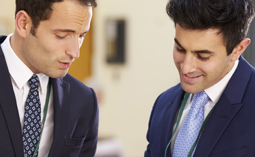 Two men in suits looking down at something.