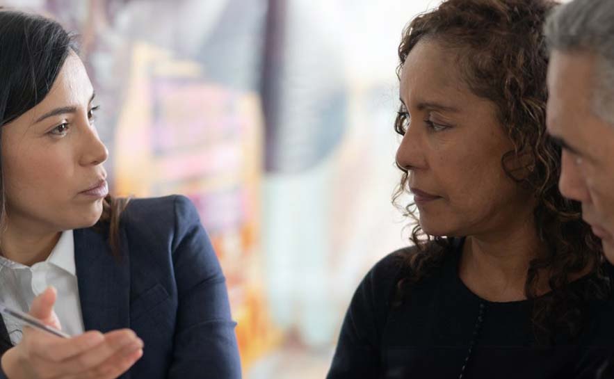 Three people engaged in a serious conversation.
