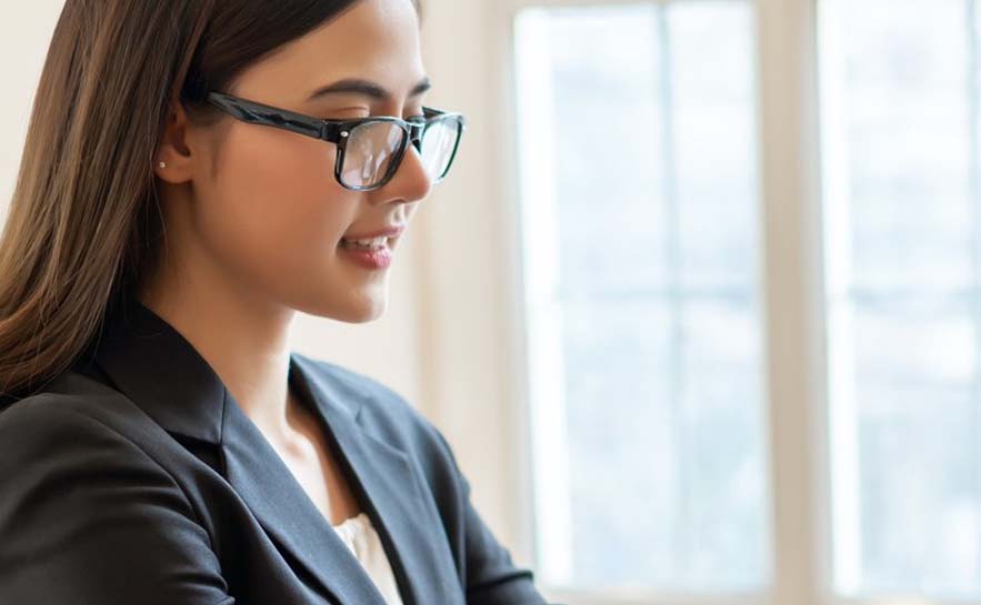 Woman with glasses in business attire looking down.