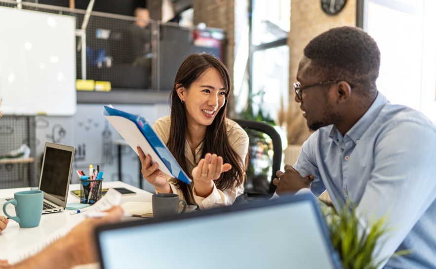 young asian woman discussing paperwork at a desk with an african american male 